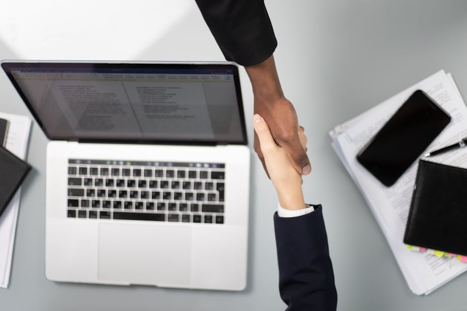 Two professionals shaking hands over a business partnership agreement