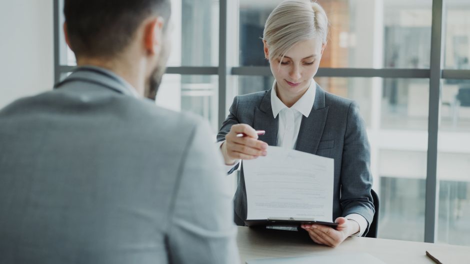 An HR professional reviewing payroll documents at a desk